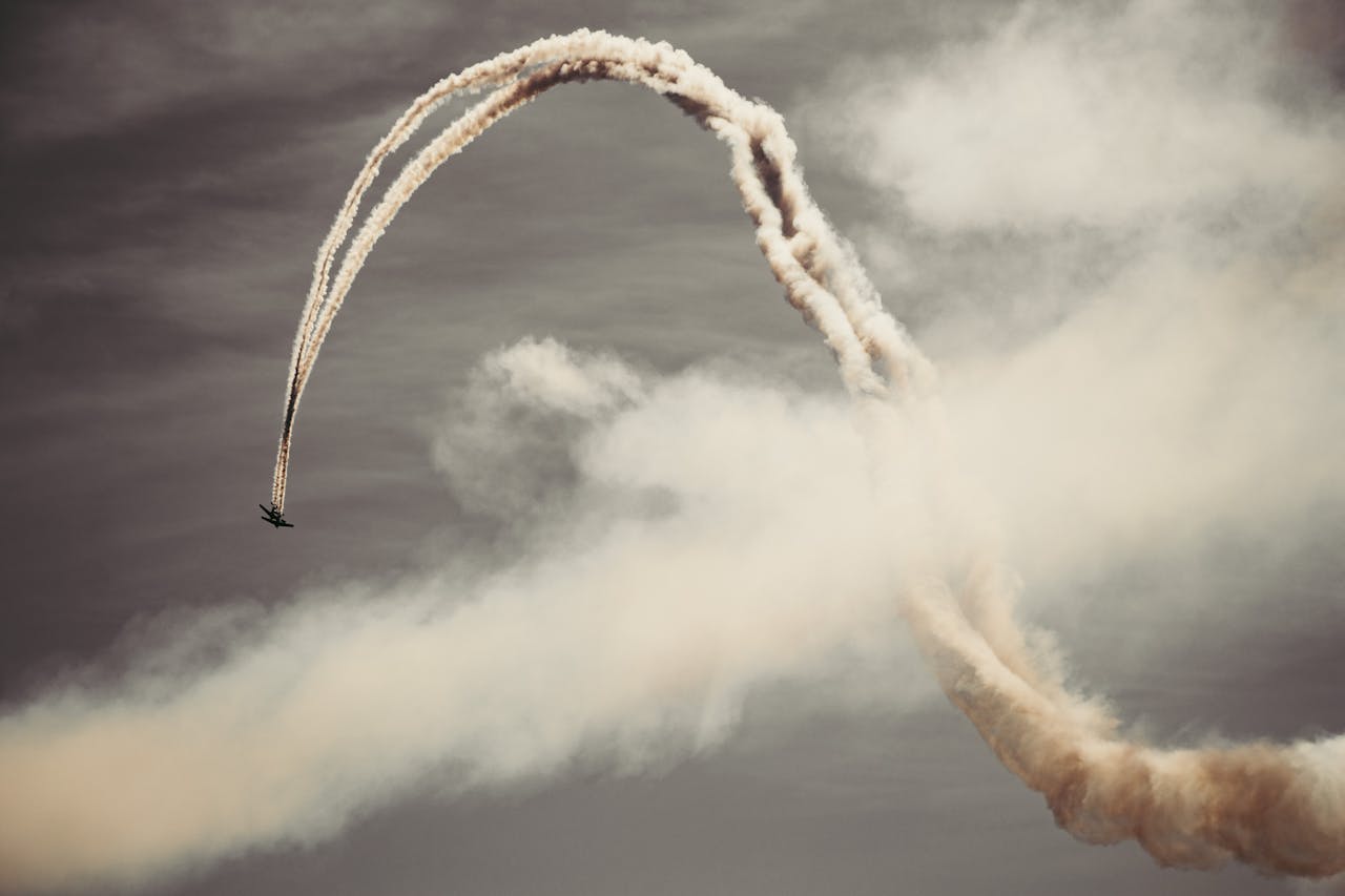 A thrilling airplane performing acrobatics in the sky with smoke trails.