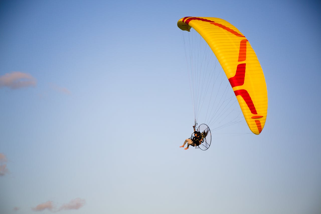 Experience thrilling paragliding against a serene blue sky backdrop.