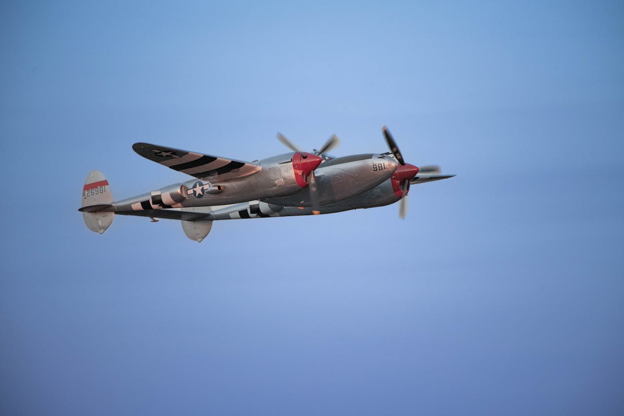 A classic military fighter aircraft soaring through a bright blue sky, capturing aviation history.